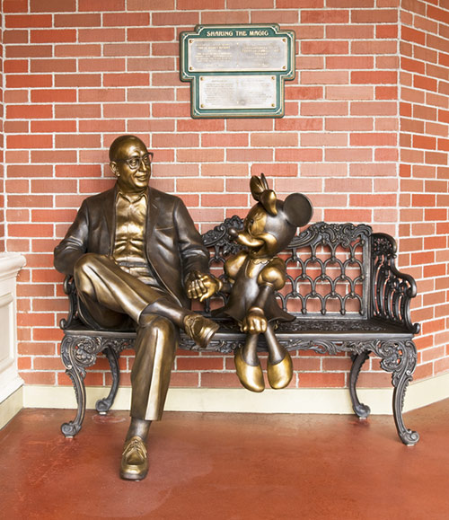 ミニーマウスと一緒にベンチに座っているある人物の像